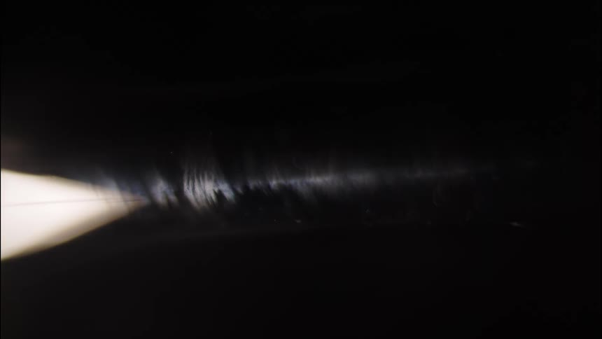 A closeup of a vinyl record with light reflecting off its grooves in the dark