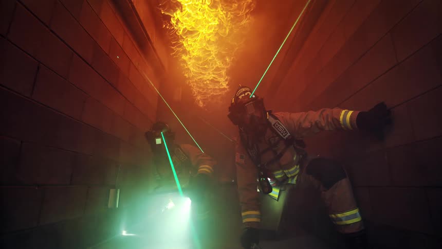 Firefighters crawl under the flame down the hall
