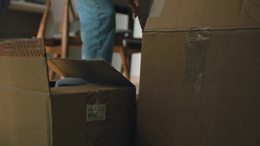 A person is placing cardboard boxes on the floor in a home setting