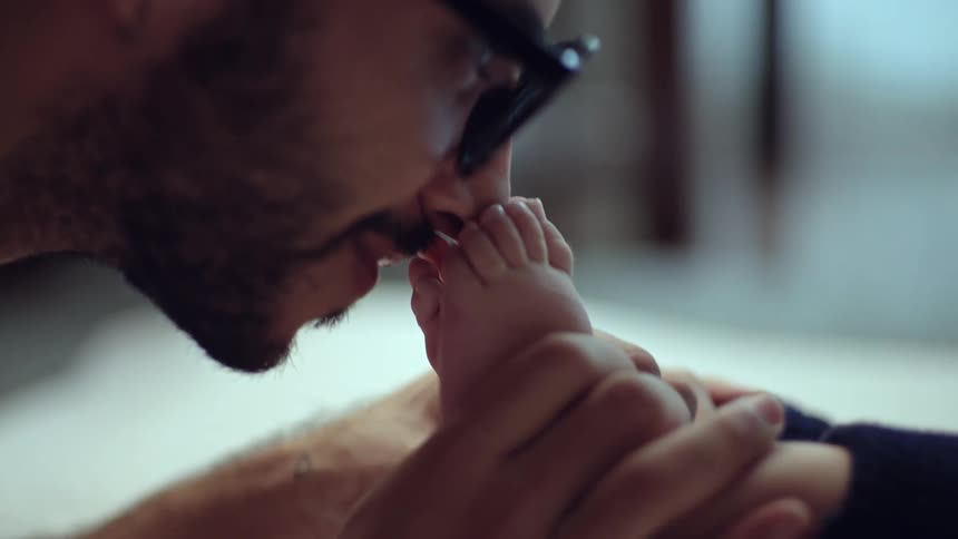 A man gently kisses a babys foot in a tender closeup moment