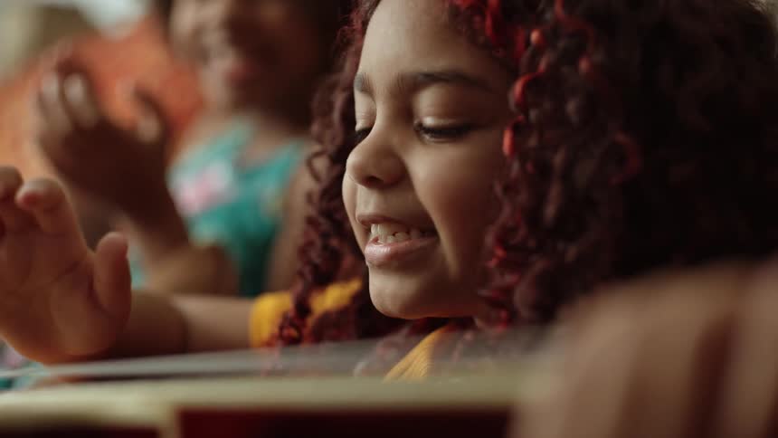 Children smile and clap as a guitar is played