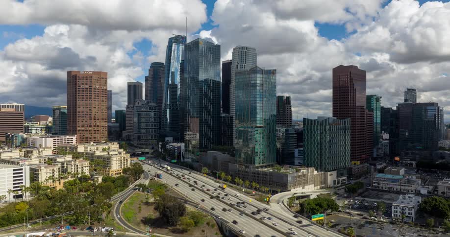 A busy highway cuts through downtown Los Angeles with tall glass skyscrapers