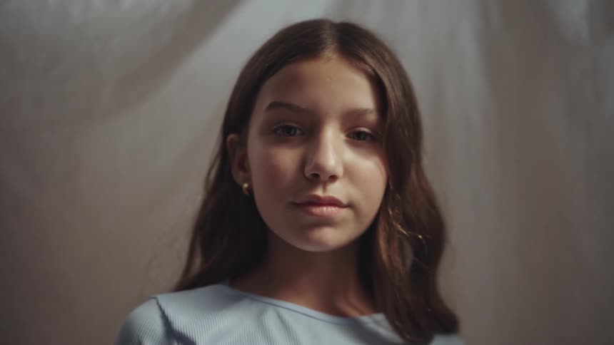 The girl is smiling in front of a white curtain