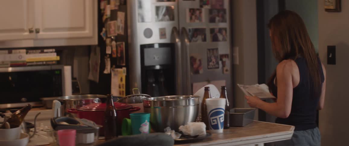A woman walks into the kitchen with her mail