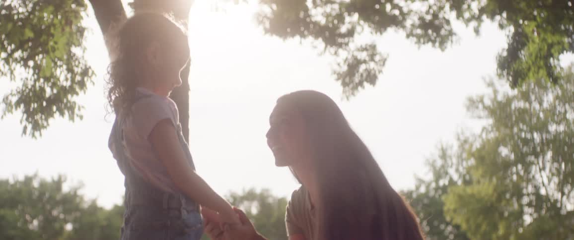 A mother is kneeling before her daughter and talking to her
