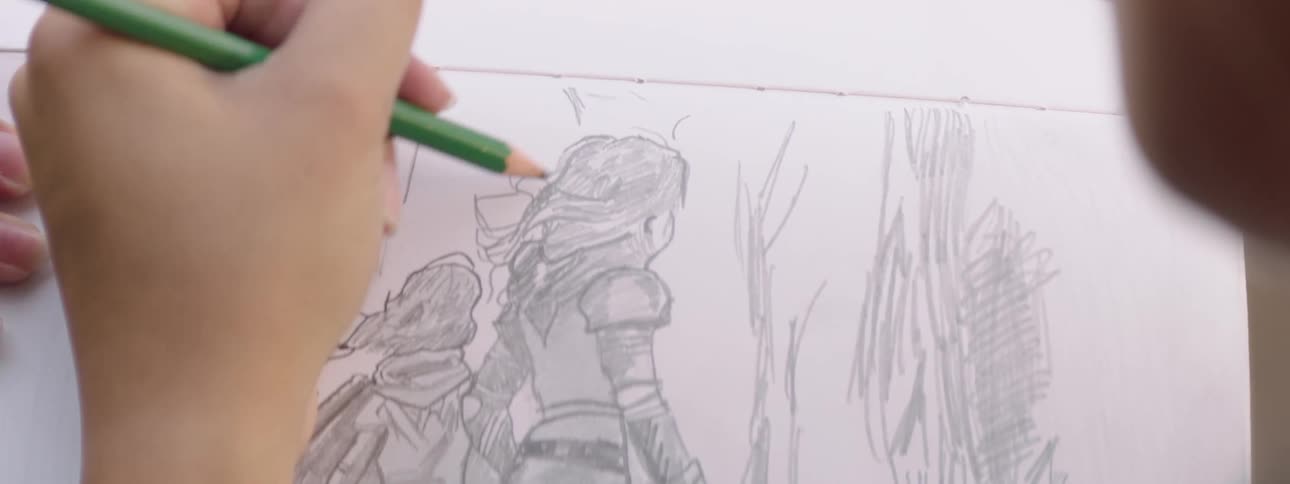 Close up of a teenage girl sketching in a sketchbook while sitting outdoors during daytime