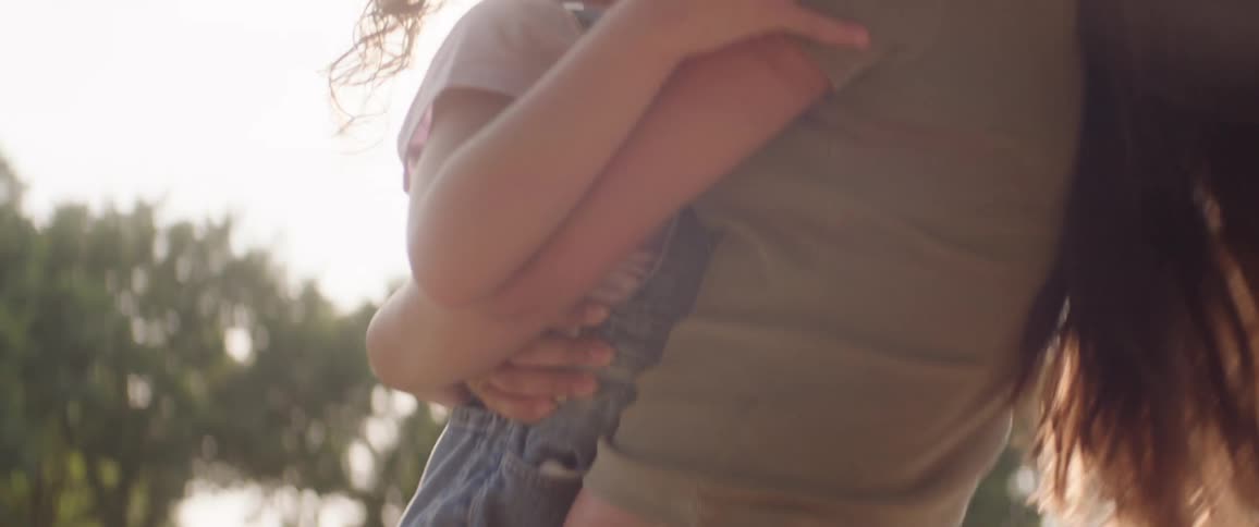 The sun shines on a mother hugging her daughter