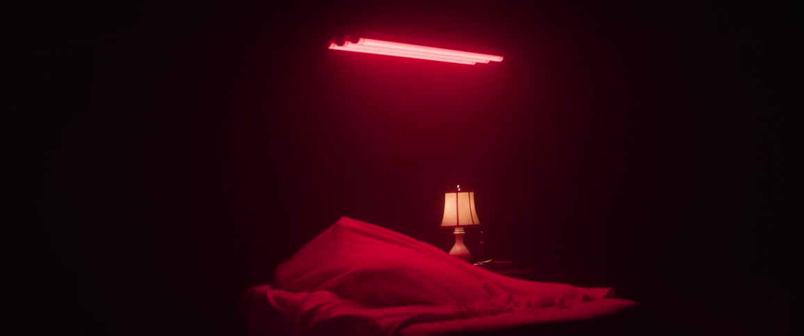 A woman is sleeping in a bed under a red light