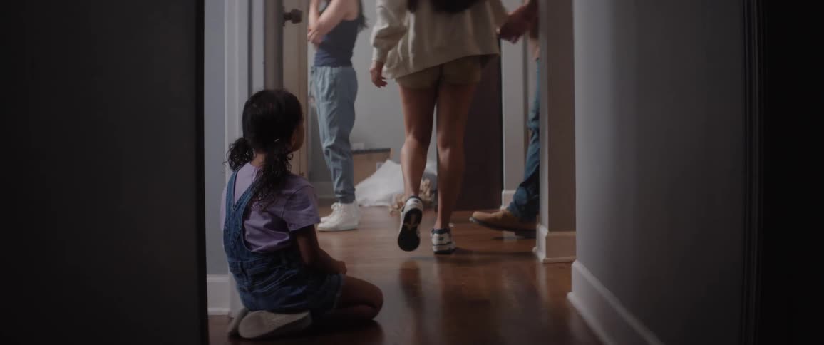 A man helps a teenager stand up in the hallway