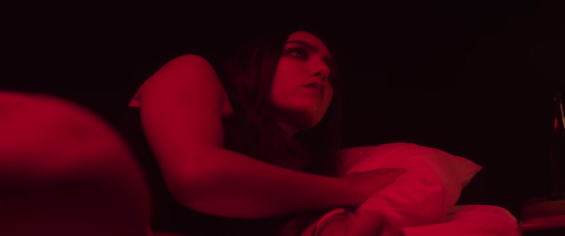 After looking toward light shining at her face a woman lowers her head to her pillow to fall asleep