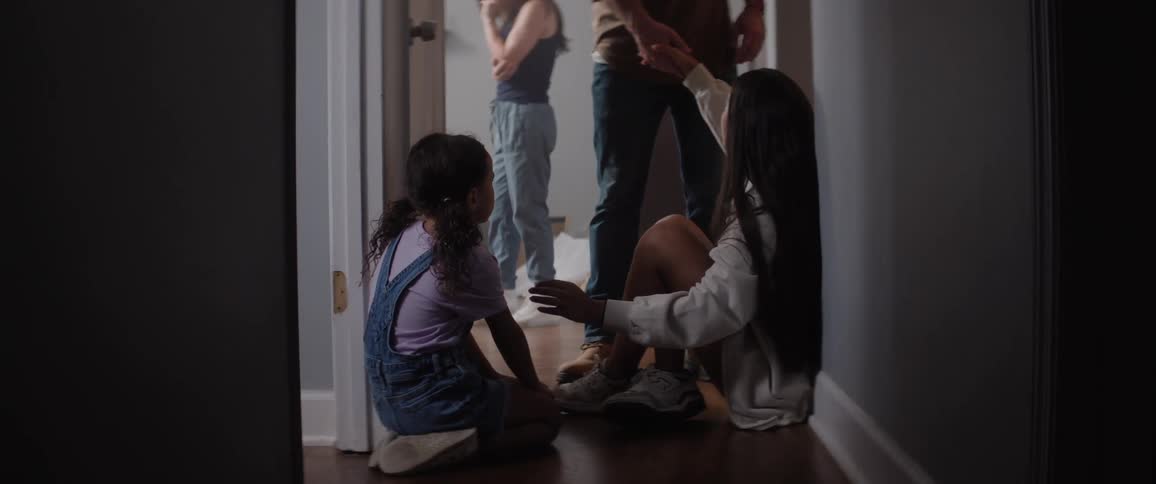A man helps his daughter stand in the hallway