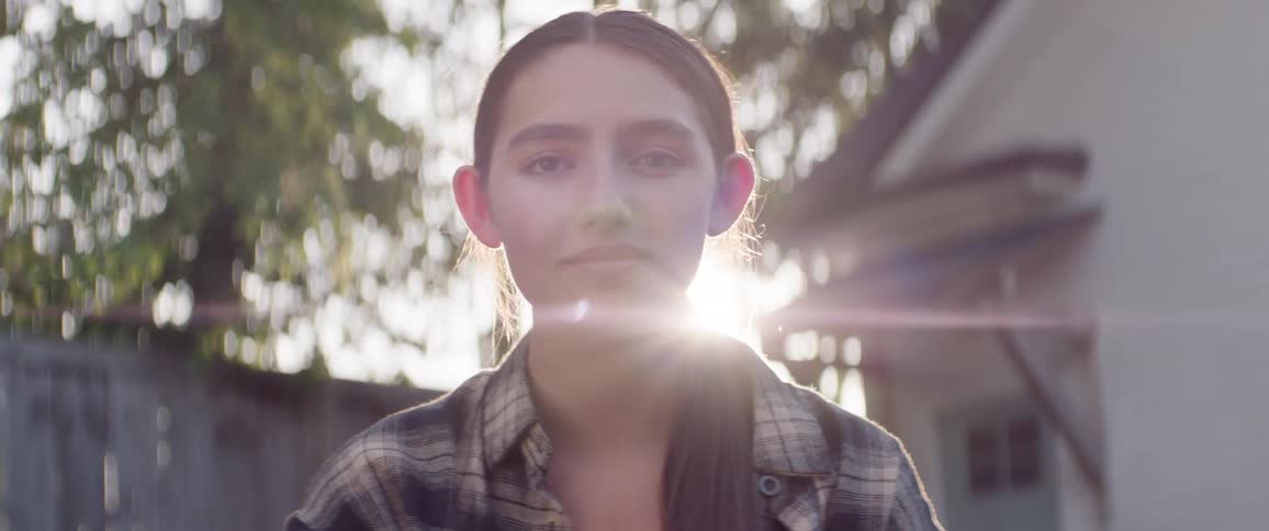 Close up portrait of a female teenager standing and smiling outdoors during daytime