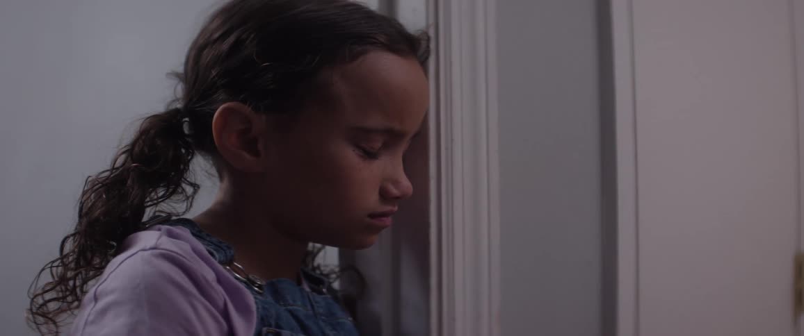 A little girl sits in a room alone looking very sad
