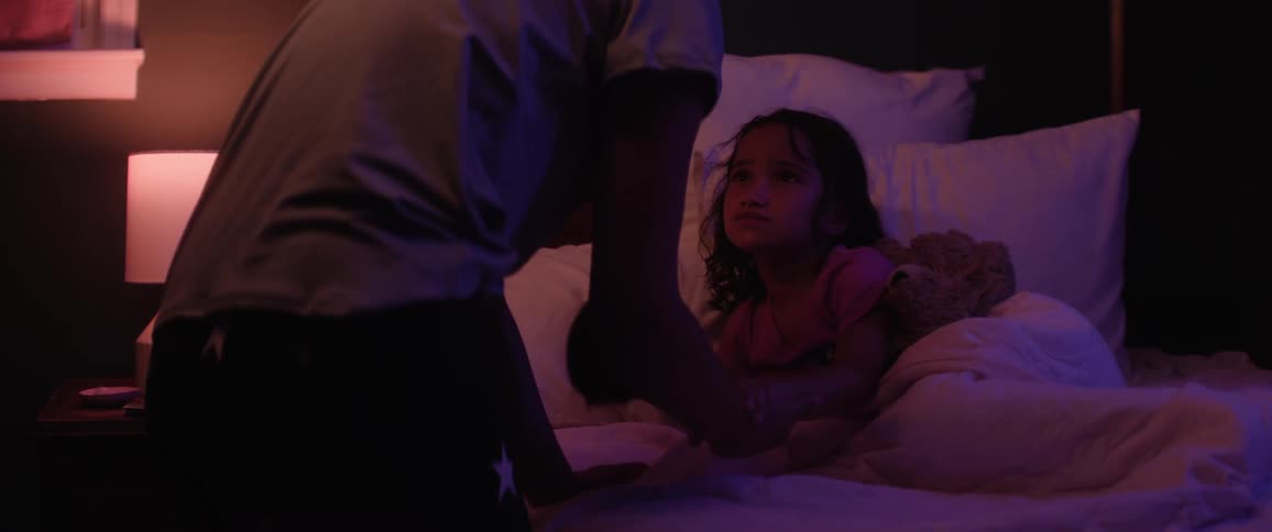 Parent tucks in and comforts their daughter in her bed