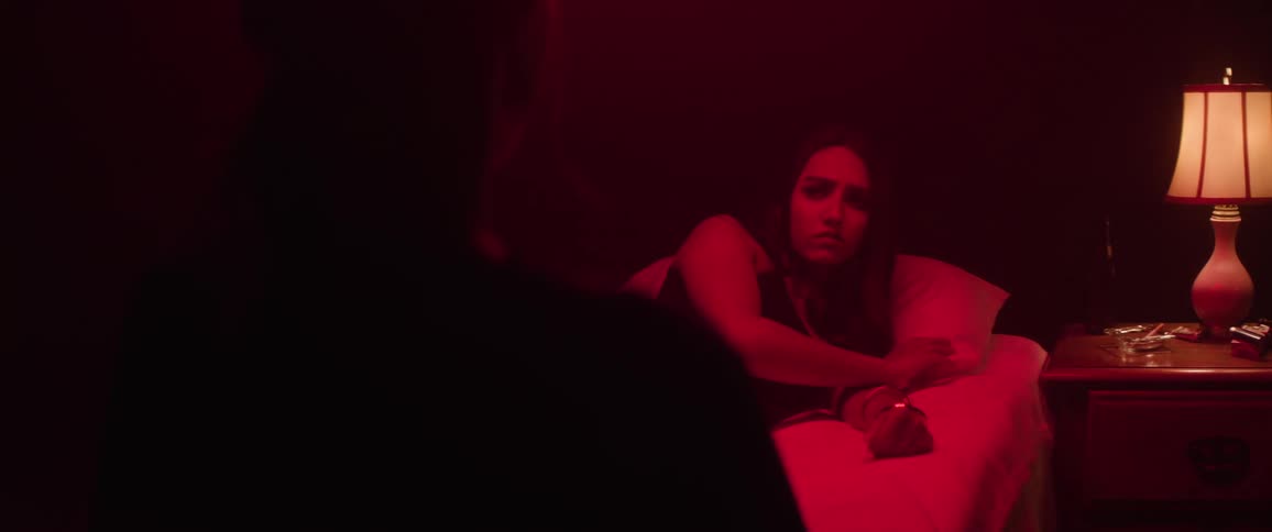 A woman lays in bed while another person watches her