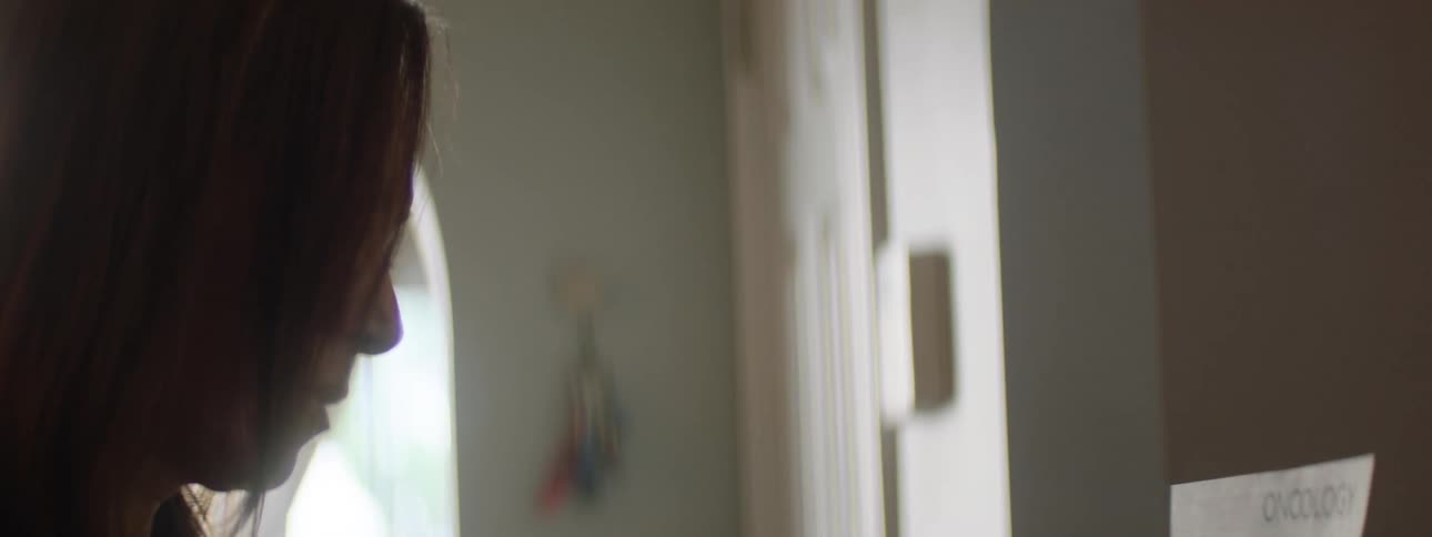 Woman sits at home looking at her bills