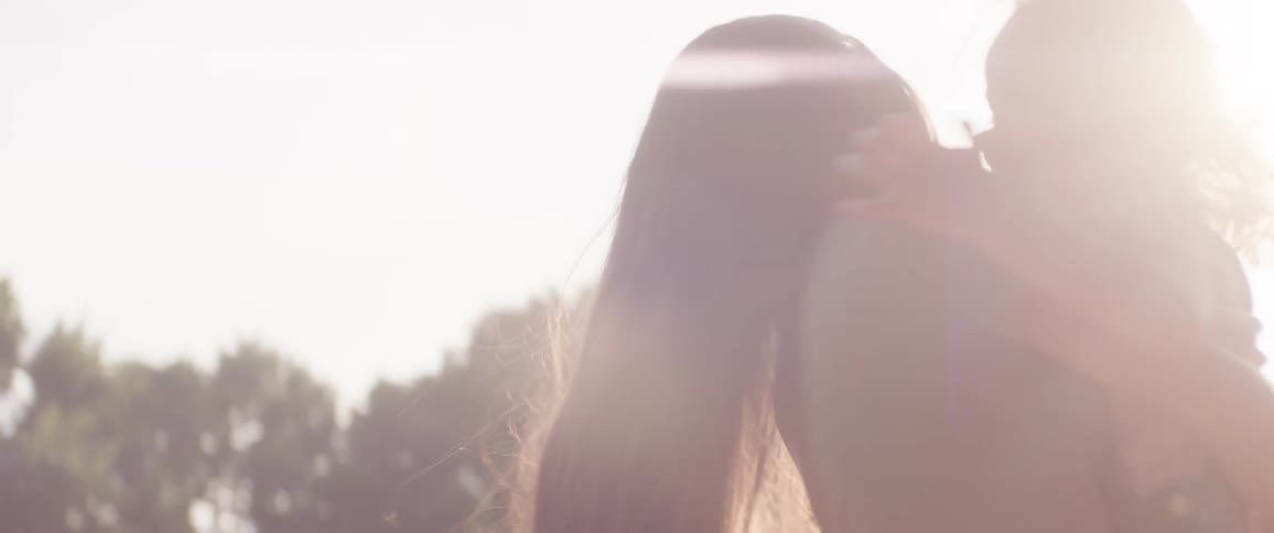 Two sisters smile and laugh together outdoors in the sunlight