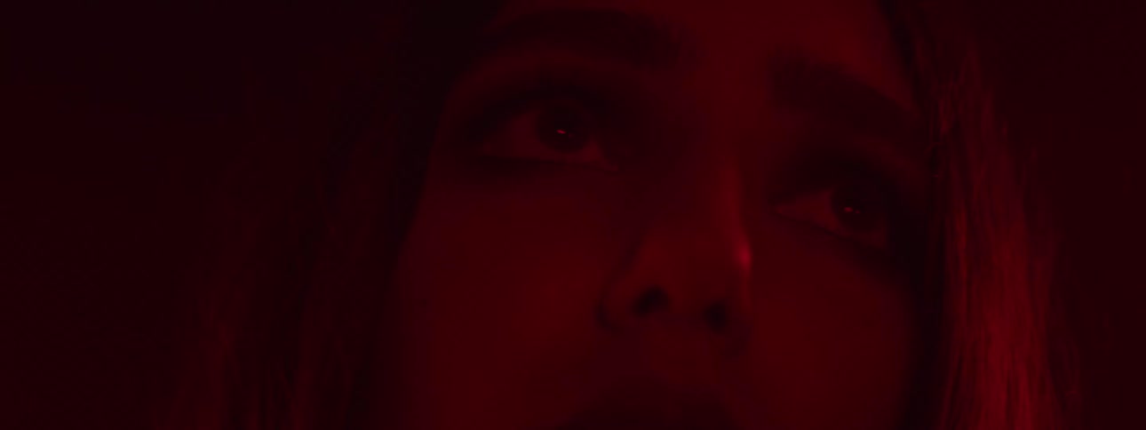 Man grips the shoulder of a fearful woman as she looks back at him