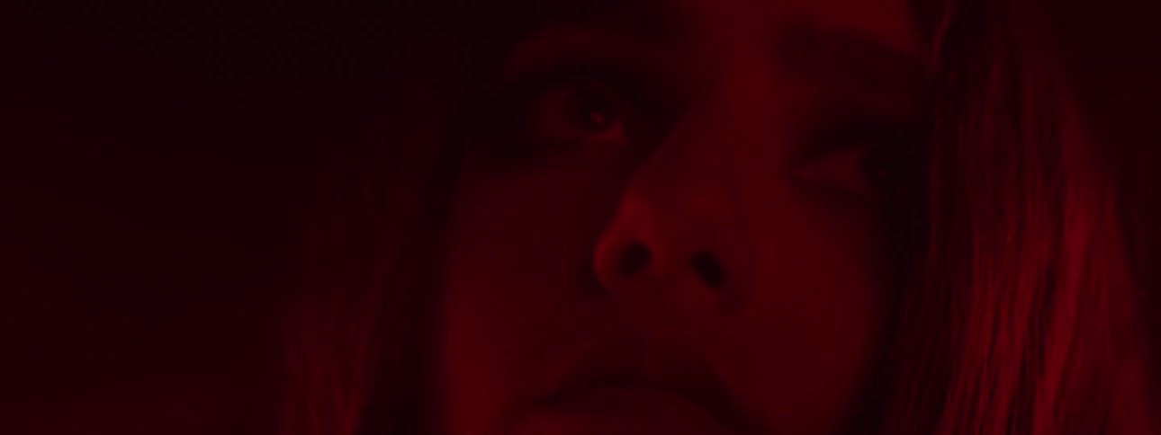 A woman looks scared in the dark room