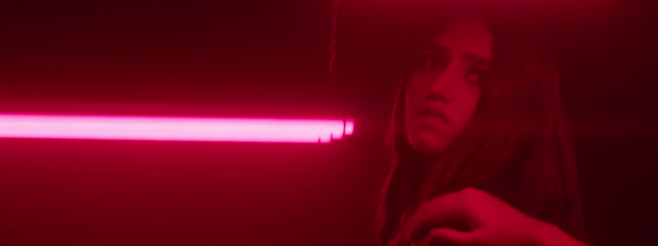 Woman in a lowlight environment and a person with a hand on her shoulder