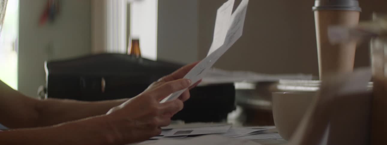 A woman goes through a document while sitting at a desk with a coffee cup resting on top of a printer at midday