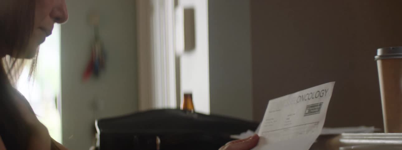 A woman is crying while reading a piece of mail
