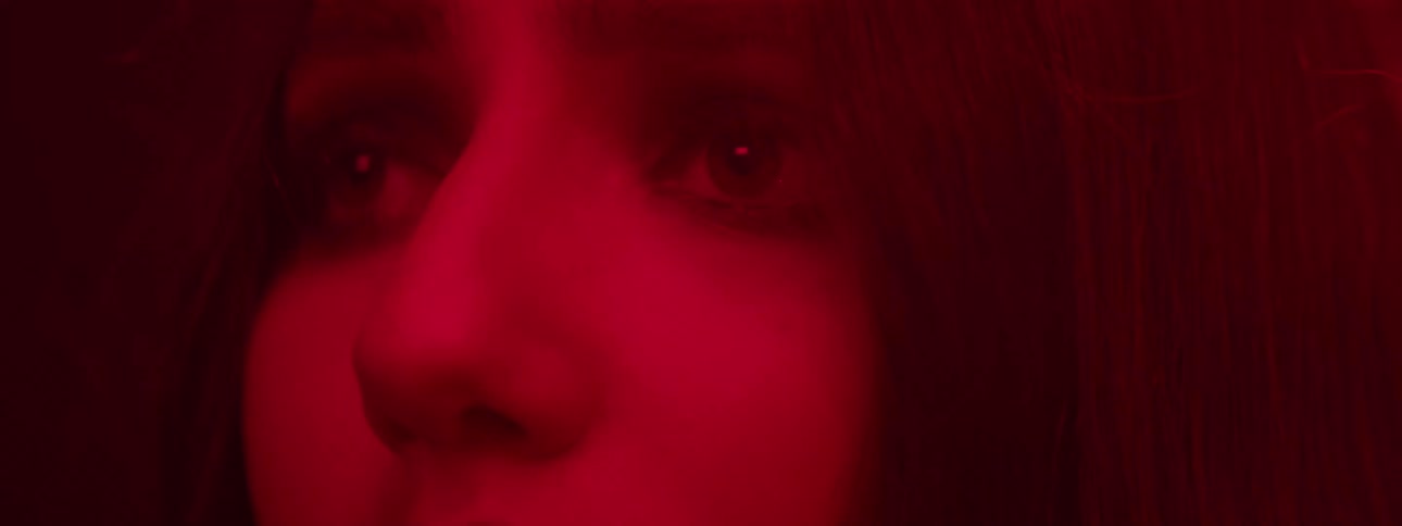 Upset woman stares in an area lit by red lighting