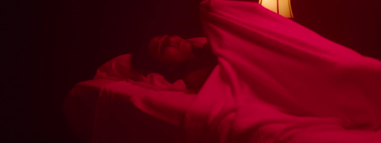 A girl looks sad as she covers her head in a blanket