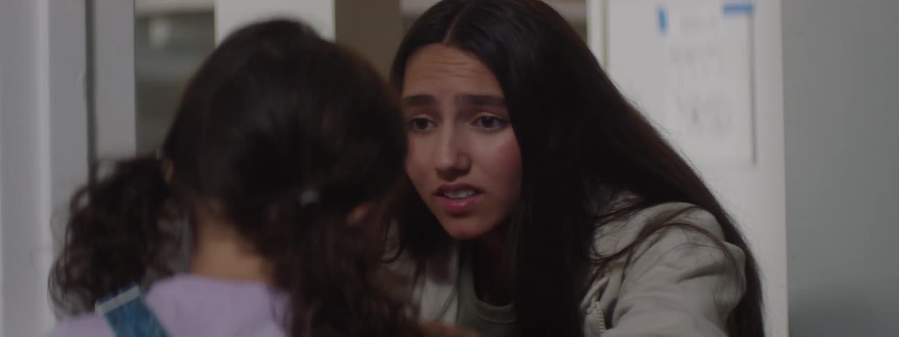 Young woman talks to a girl before standing up with the help of an adult male