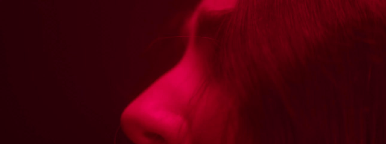 Black haired woman in a dark room with low red light
