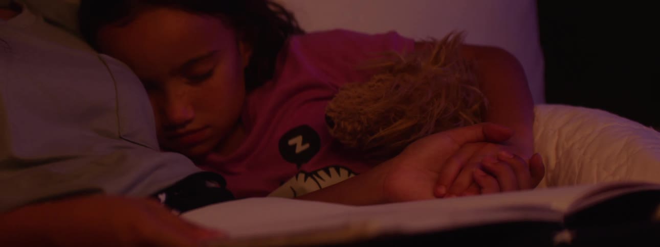 A girl is sleeping and holding hands with another girl in bed