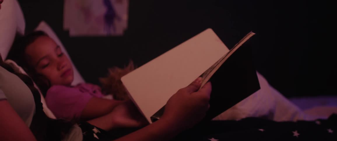 A girl shows her sister drawings in a book