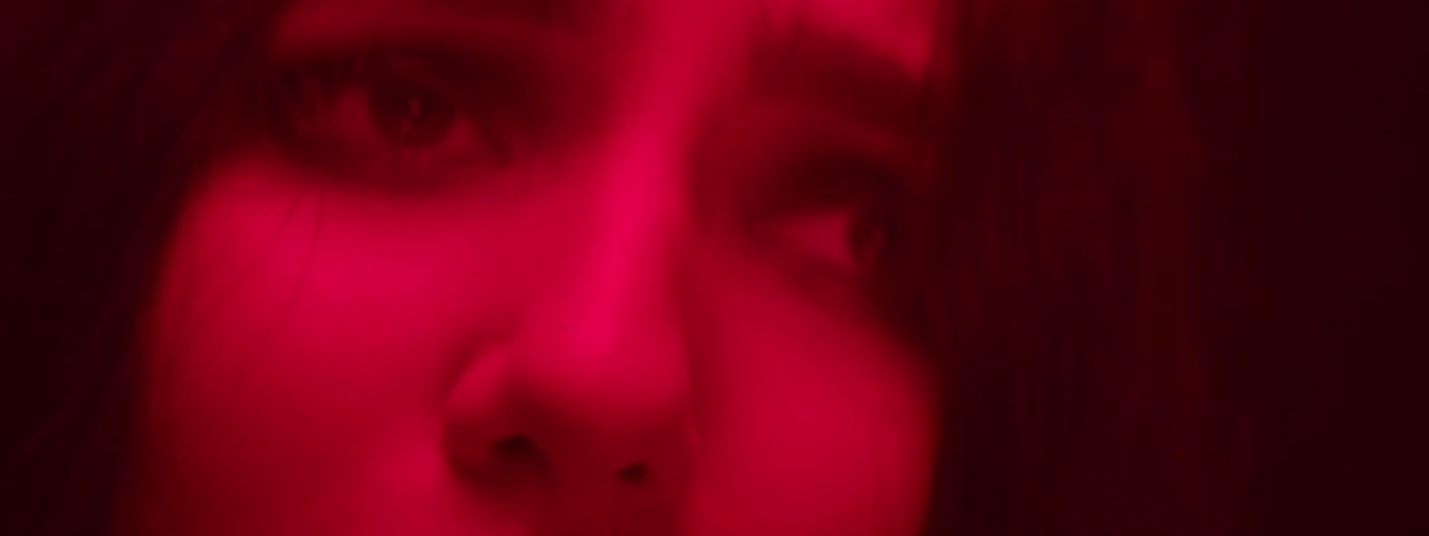 A womans in a close view bathed in red light with her eyes open