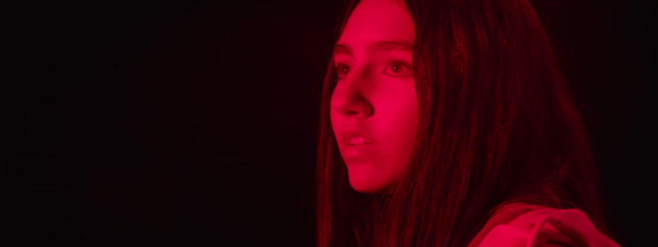 Woman in red light tracks a person or object walking to her right