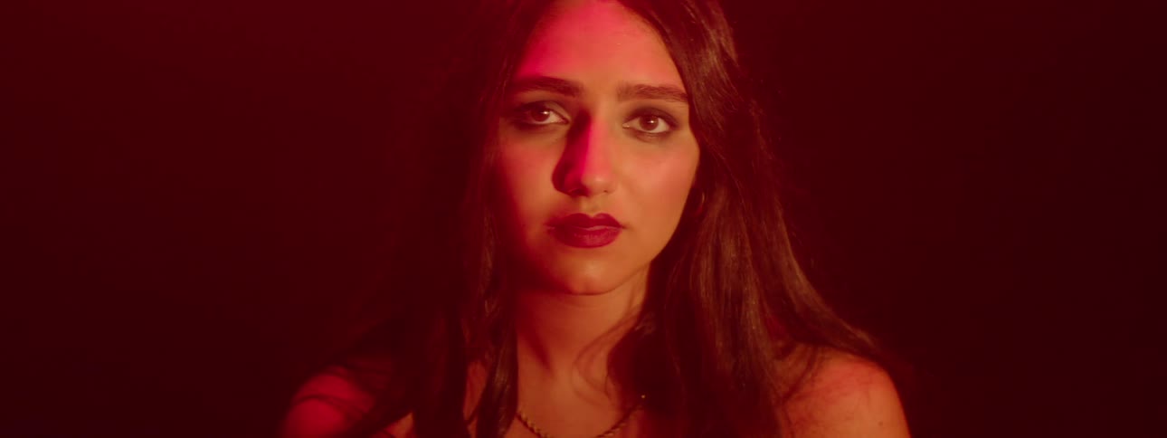 Close up portrait of a young woman standing in room with dim red lighting