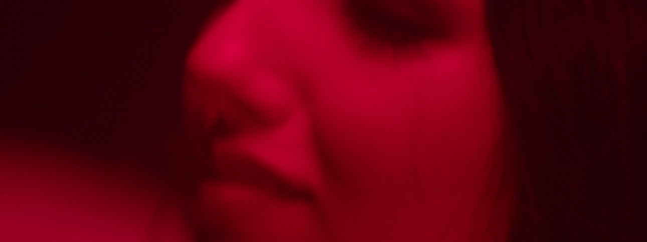 Portrait of a woman with focus on her eyes in a lowlight space with red light