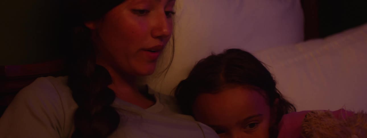 Mother reads a story to her daughter in bed