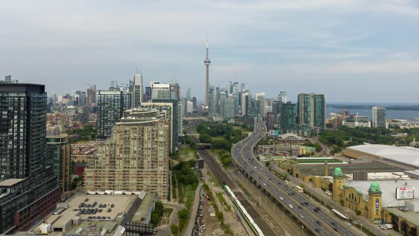 Aerial view of a cityscape with highways leading toward the skyline and a tall tower at the center