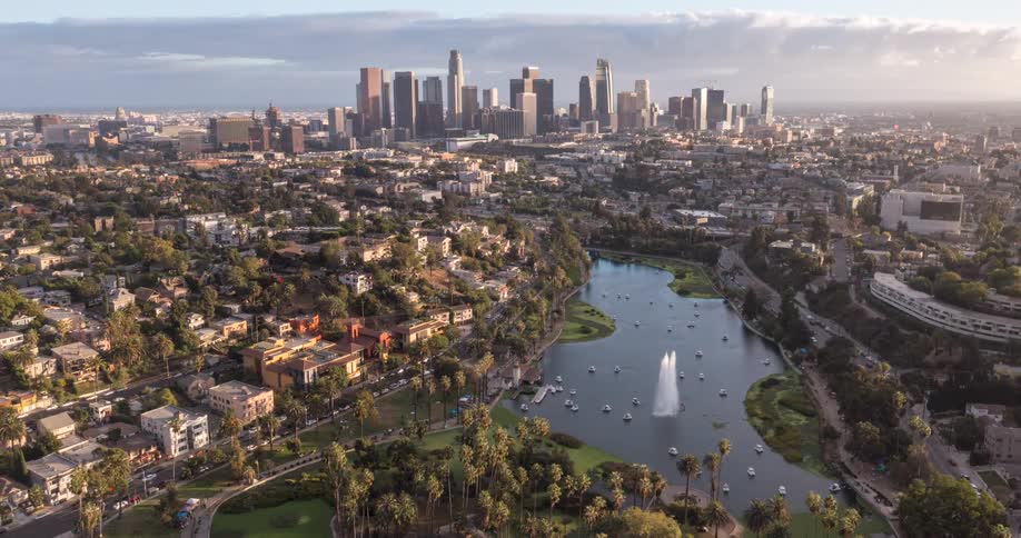 Highway traffic passes a busy Echo Park lake a distance from the  Los Angeles city skyline on a cloudy day