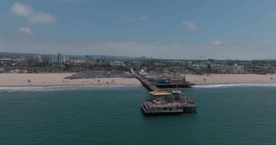 Santa monica pier beach with the city of santa monica in the background as ocean waves hit the shore at midday