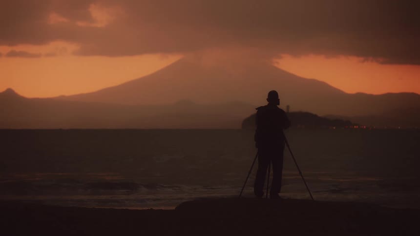 A person is setting up a tripod on the shore