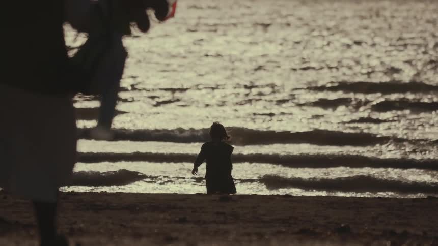 The child is walking ahead on the beach