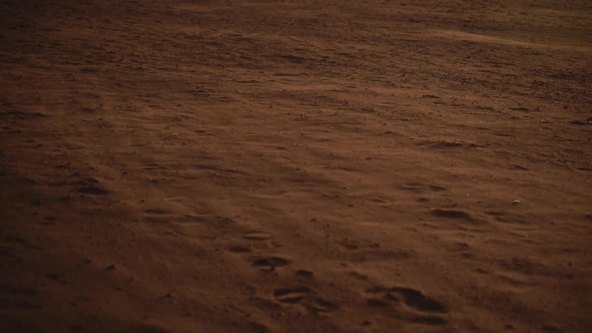 Footprints in the sand as wind blows dust across the desert floor