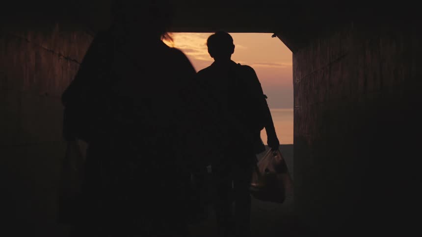 People walk through the tunnel towards the beach