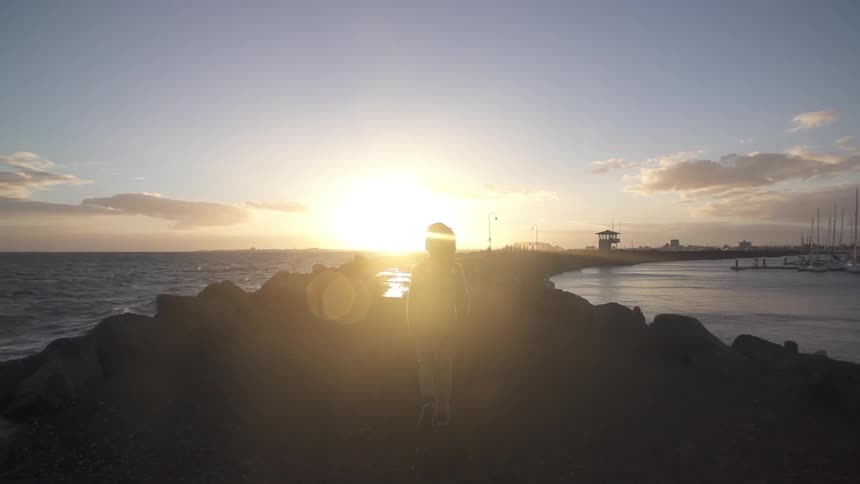 A child walks on the beach at sunset