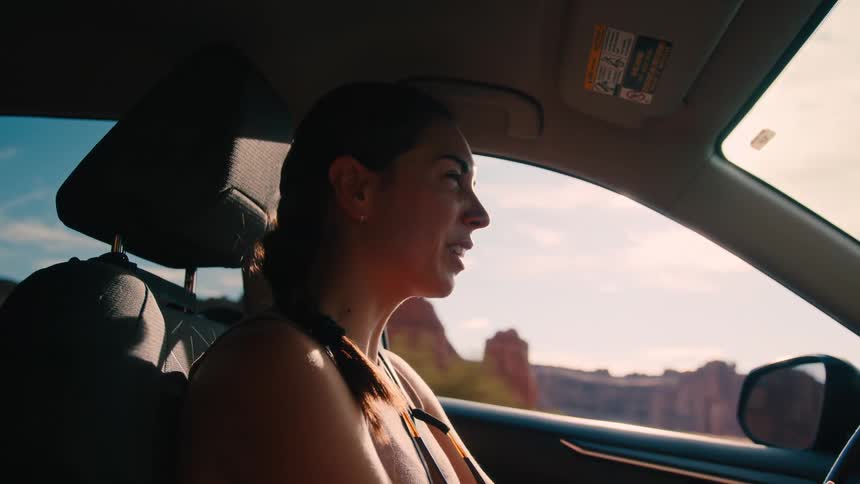 The woman is talking as she drives past the canyon