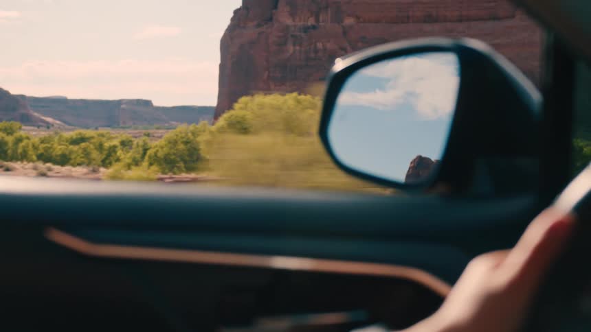 A person driving their car through the red rock desert