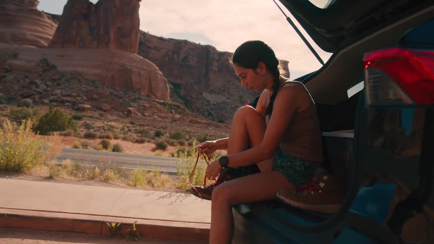 Woman sitting on trunk and wearing hiking boots