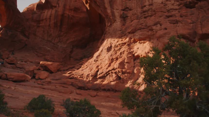 Hikers explore a massive red rock canyon under natural sunlight