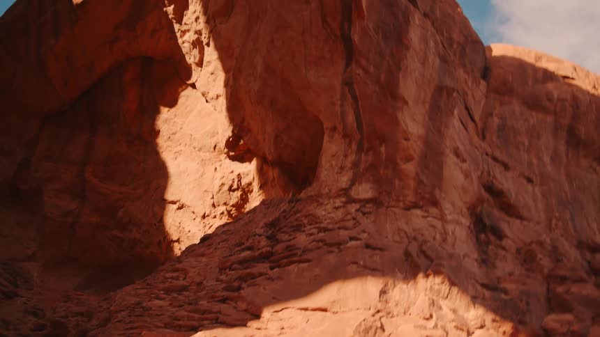 A massive natural arch made of red rock dominates the frame with a clear blue sky visible through its opening